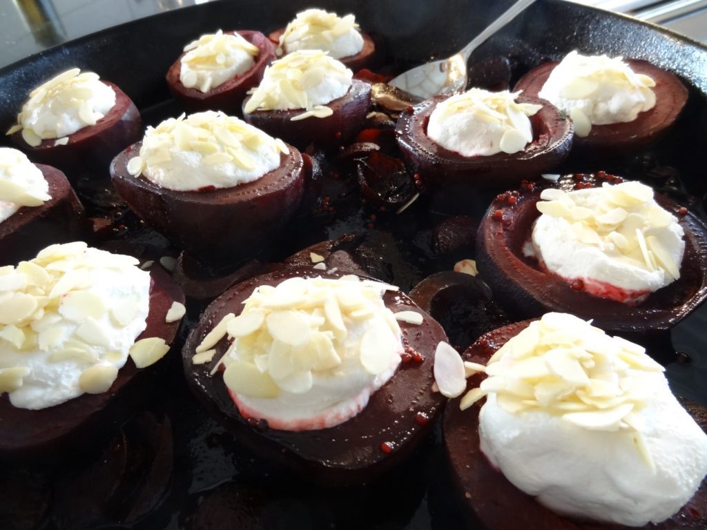 Gedünstete Rote Beete-Hälften, mit Ziegenfrischkäse gefüllt und Mandelblättchen bestreut