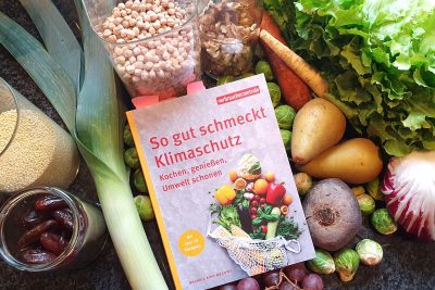 Buch mit dem Titel "So gut schmeckt Klimaschutz" auf Gemüse.